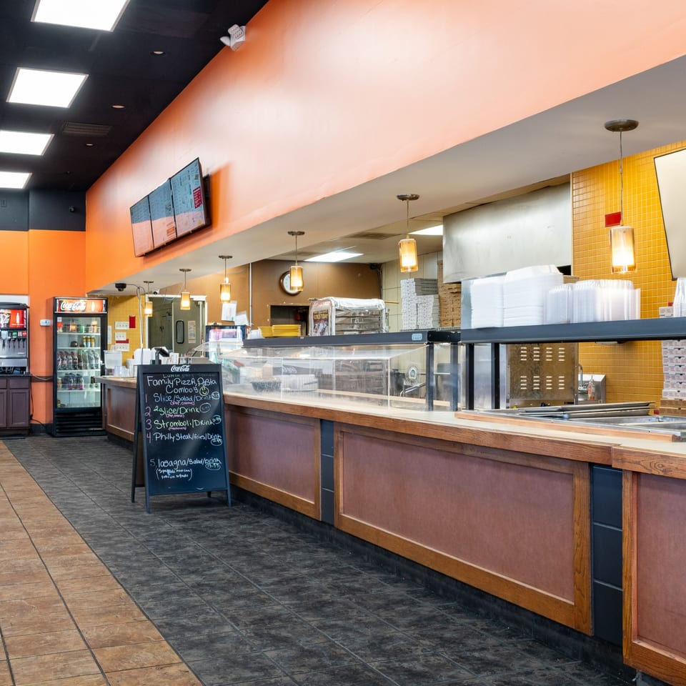 Interior of Family Pizza & Pasta Italian Eatery, featuring a counter, menu board, and drink refrigerators.