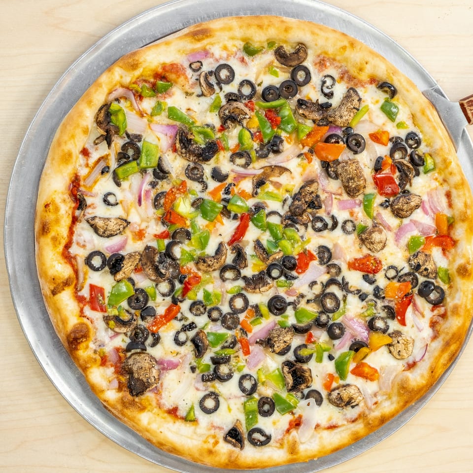 A Family Pizza & Pasta Italian Eatery pizza with mushrooms, olives, onions, and bell peppers.