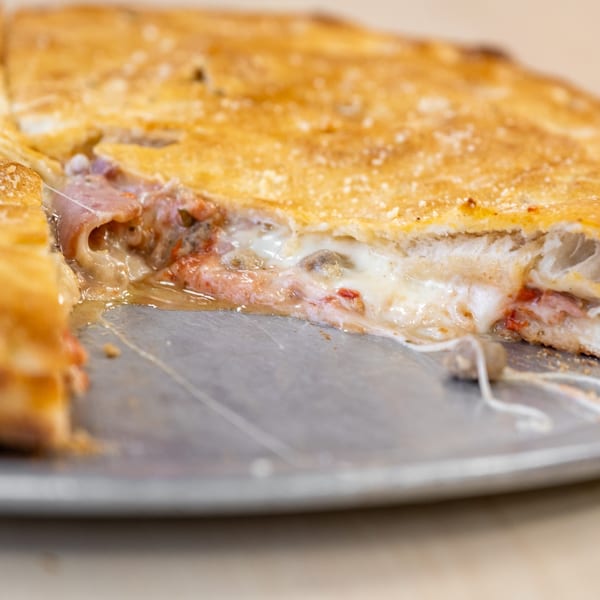 Close-up of a sliced calzone from Family Pizza & Pasta, revealing melted cheese and fillings.